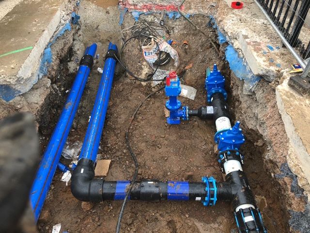 Tranchée ouverte sur un réseau d'eau, vannes et canalisations posées avant remblai